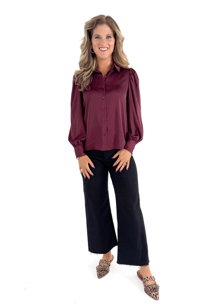 Front view of woman wearing Plum Satin Button Up Top with jeans against white studio background.