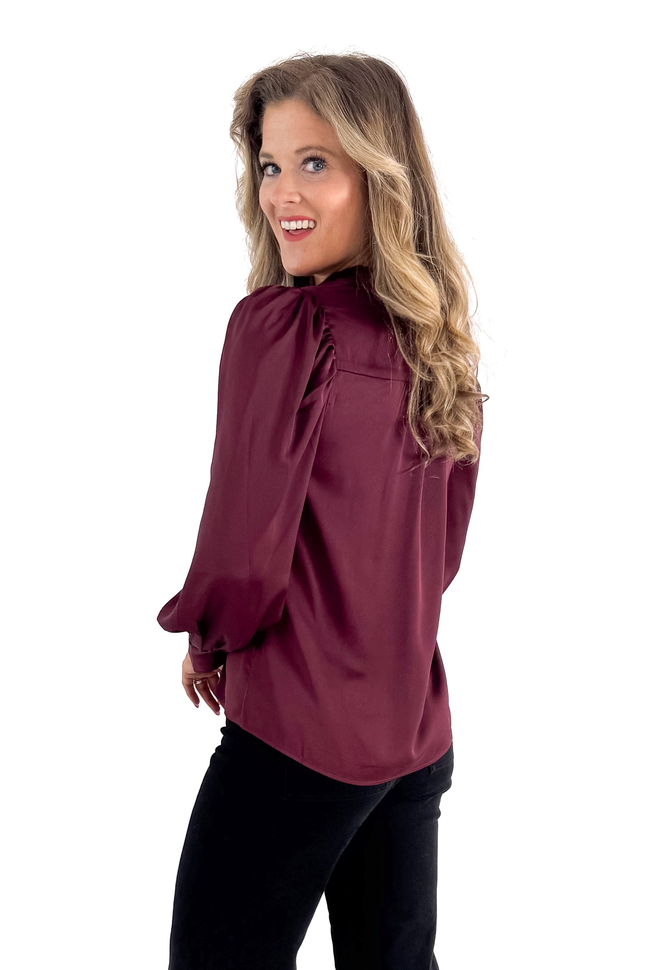 Side view of woman wearing Plum Satin Button Up Top with jeans against white studio background.