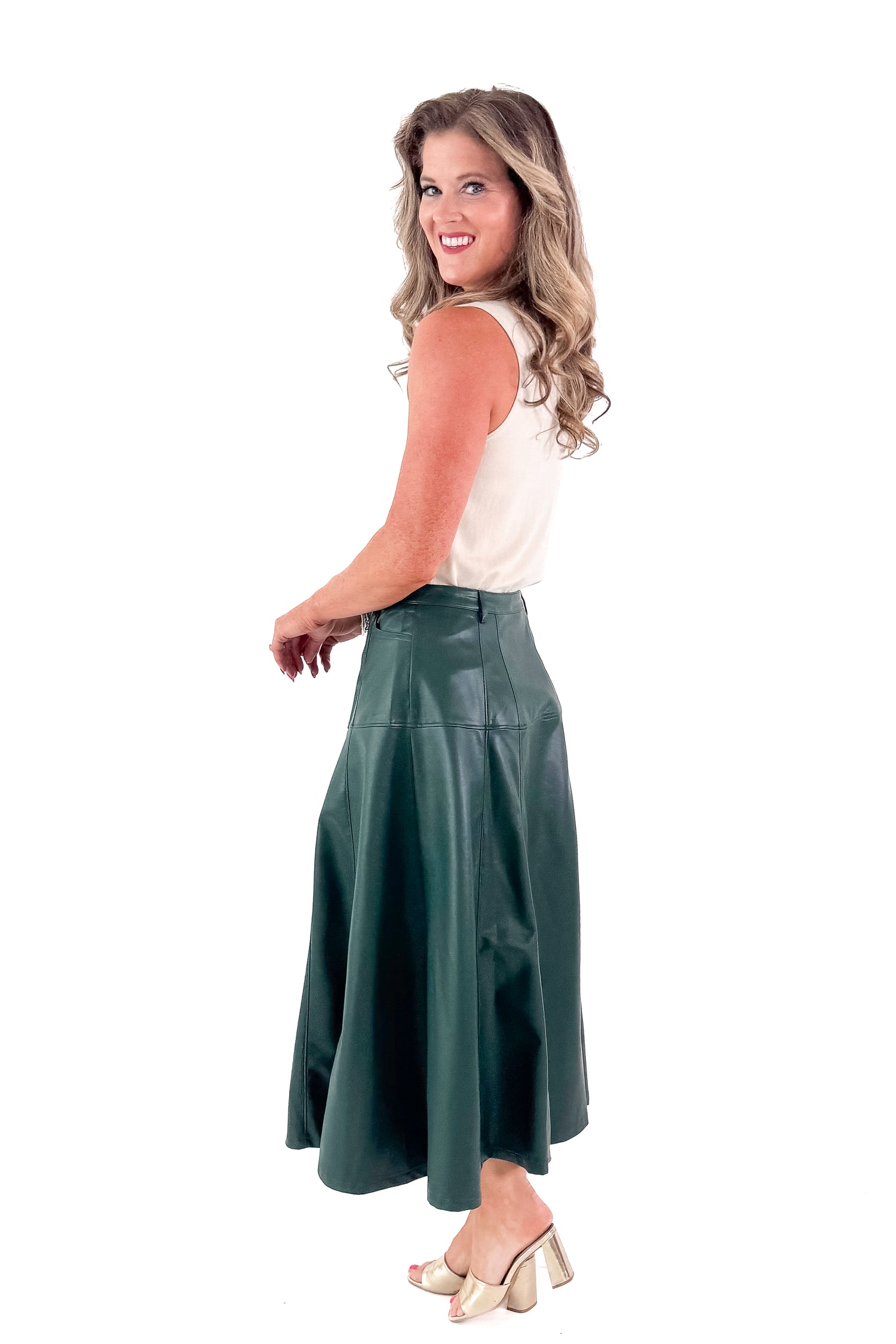 Side view of woman wearing Cream Fitted Mock Neck Sleeveless Top with skirt against white studio background.