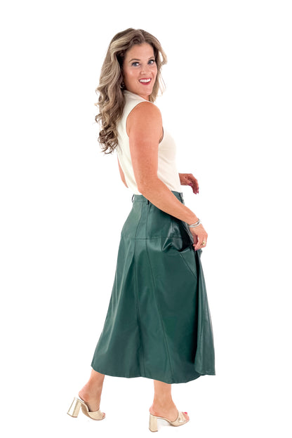 Side view of woman wearing Cream Fitted Mock Neck Sleeveless Top with skirt against white studio background.