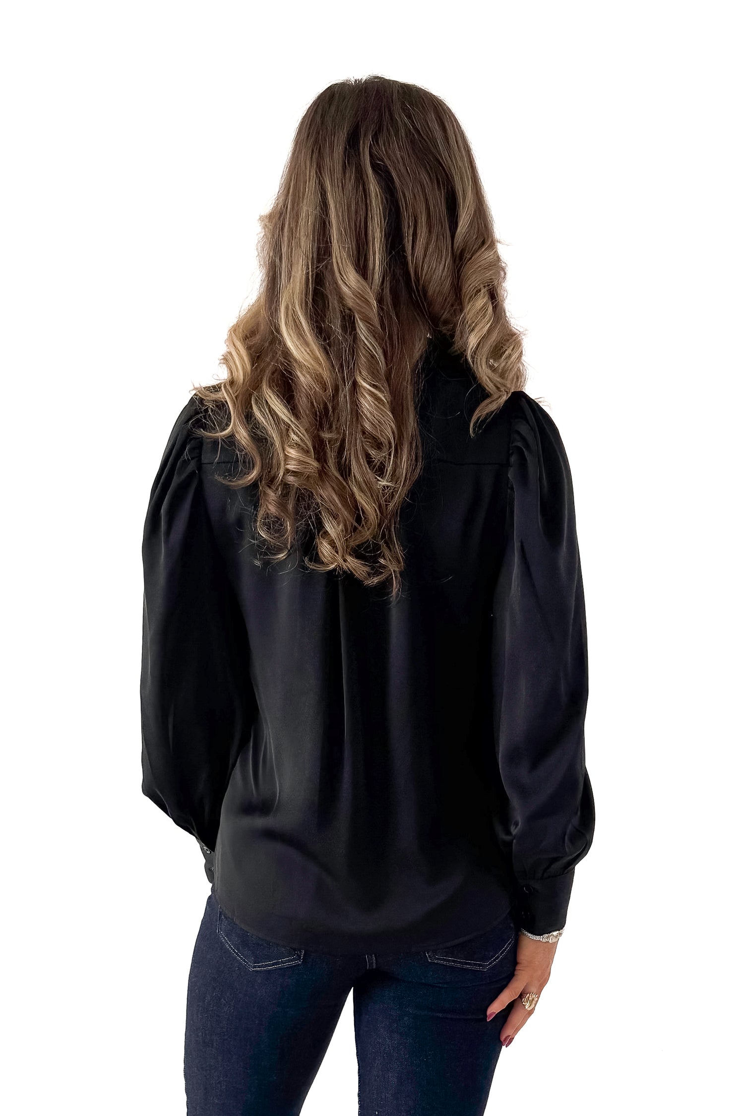 Back view of woman wearing Black Satin Button Up Top with jeans against white studio background.