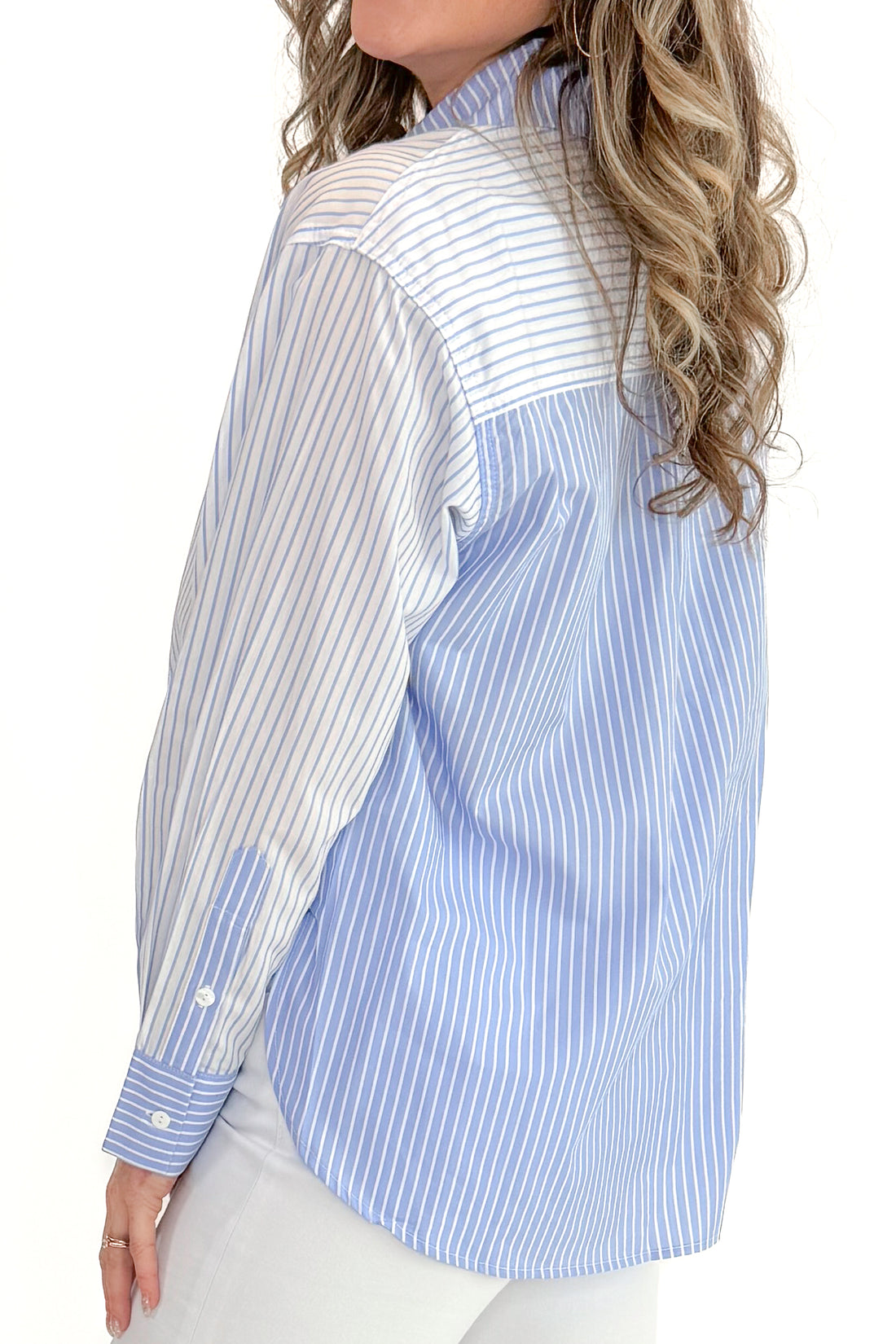 Side view of woman wearing Blue Stripe Contrast Long Sleeve Top with jeans against white studio background.