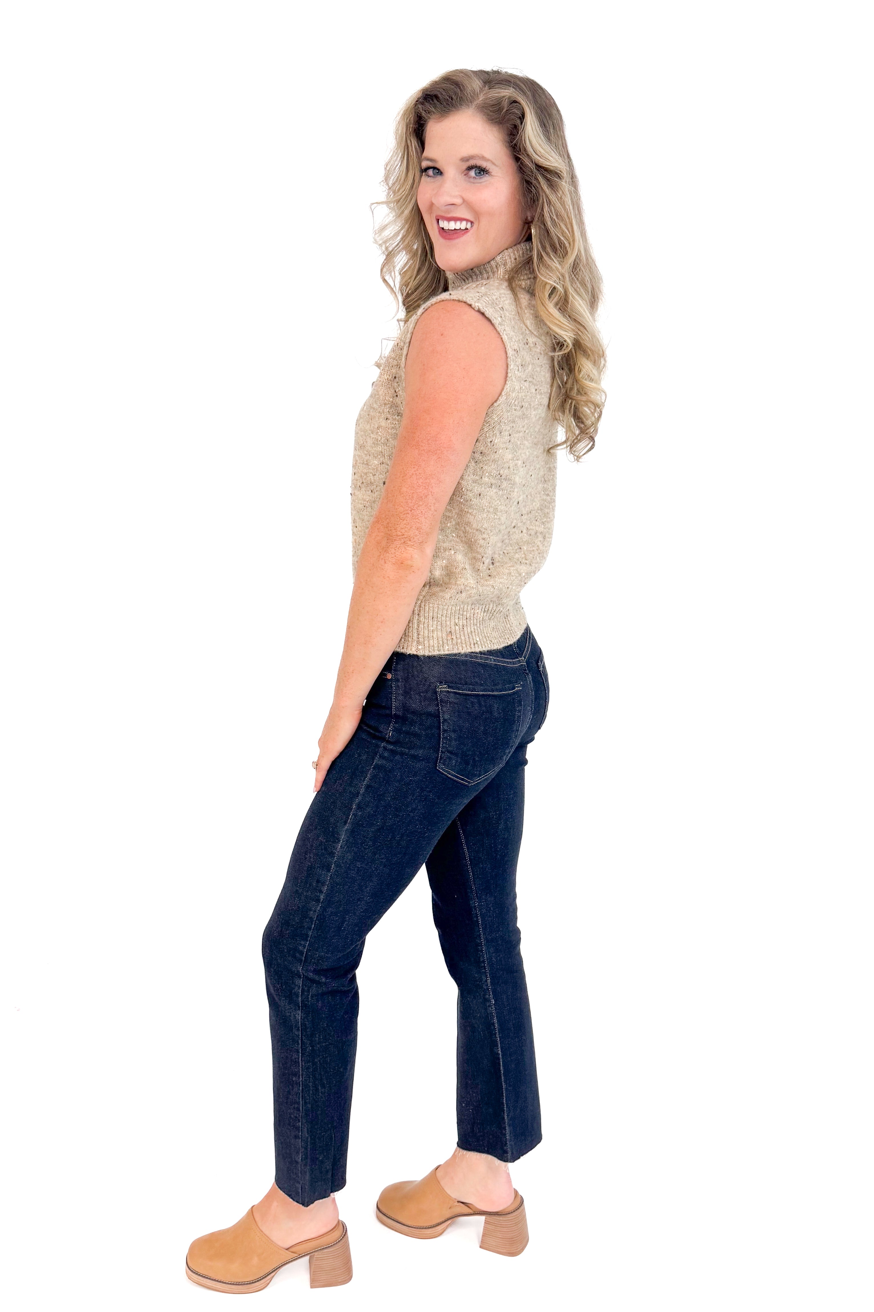 Woman wearing Sweeter Than Cider Taupe Turtleneck Sleeveless Sweater by She + Sky - side view showing turtleneck design and sleeveless cut