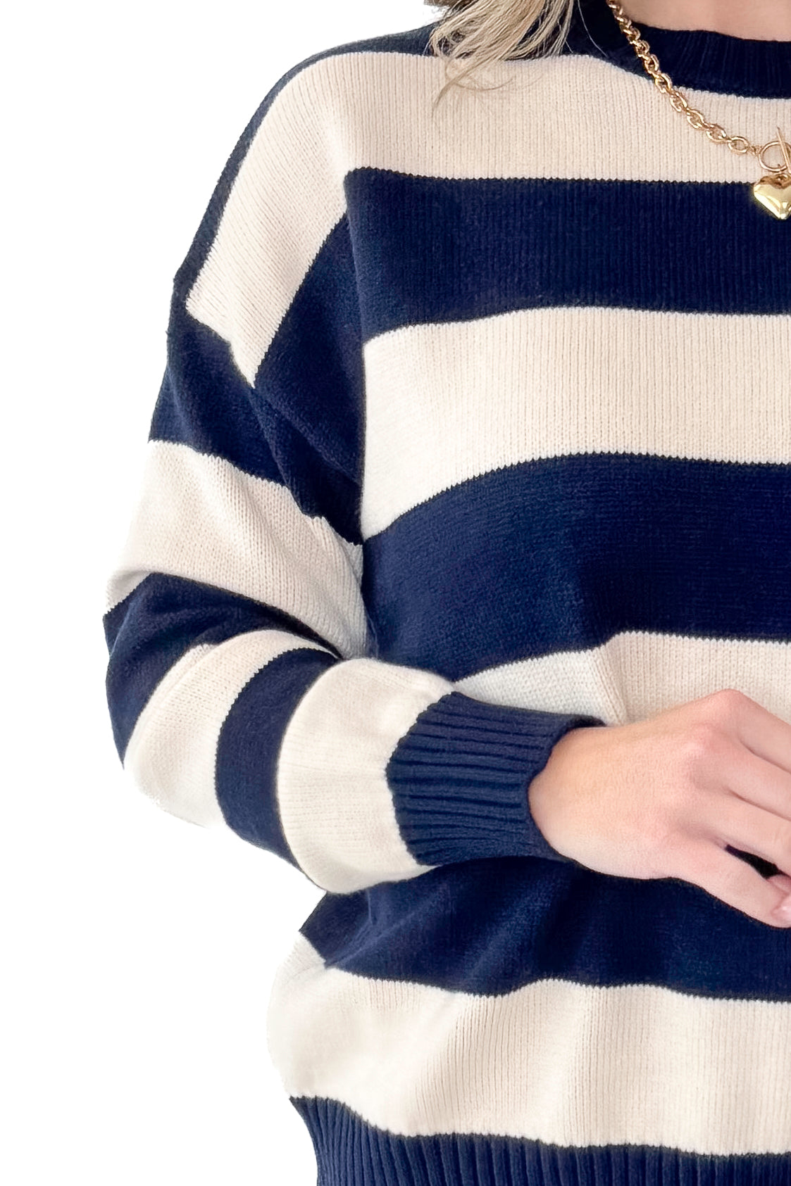 Front detailed view of woman wearing Navy and Cream Striped Sweater with jeans against white studio background.