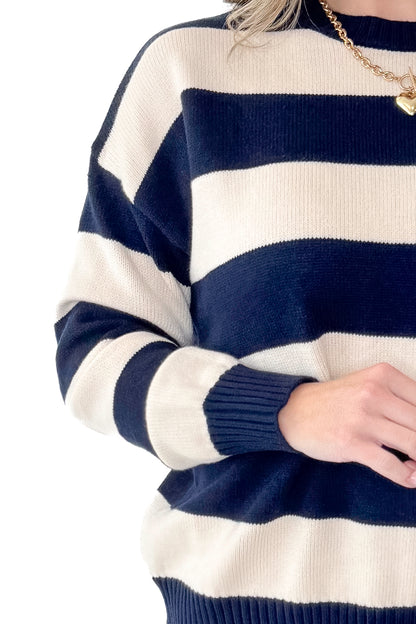 Front detailed view of woman wearing Navy and Cream Striped Sweater with jeans against white studio background.