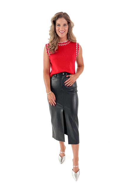 Front view of woman wearing red sleeveless sweater with black skirt with white studio background.
