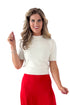 Front view of woman wearing Cream Fuzzy Short Sleeve Sweater with red skirt pants against white studio background.