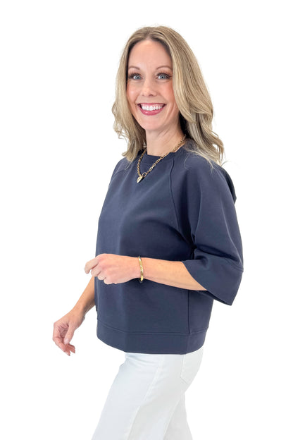 Side view of woman wearing Navy Super Soft Half Sleeve Top with jeans against white studio background.