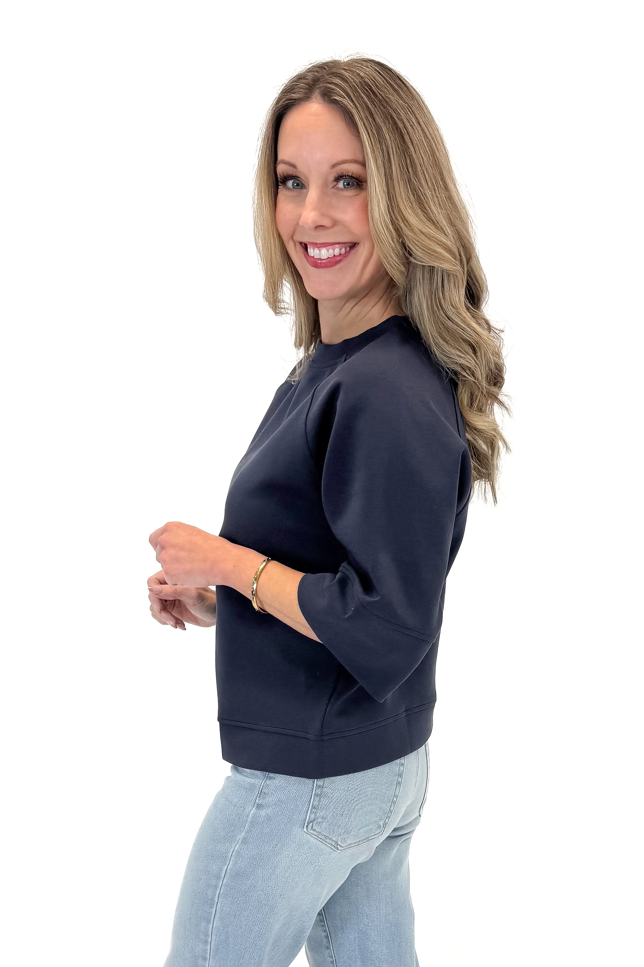 Side view of woman wearing Navy Super Soft Half Sleeve Top with jeans against white studio background.