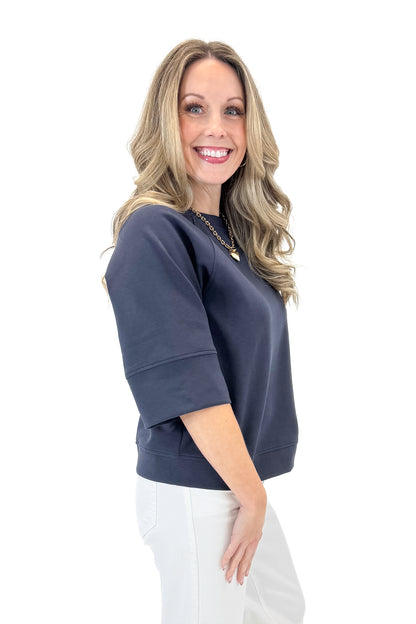 Side view of woman wearing Navy Super Soft Half Sleeve Top with jeans against white studio background.