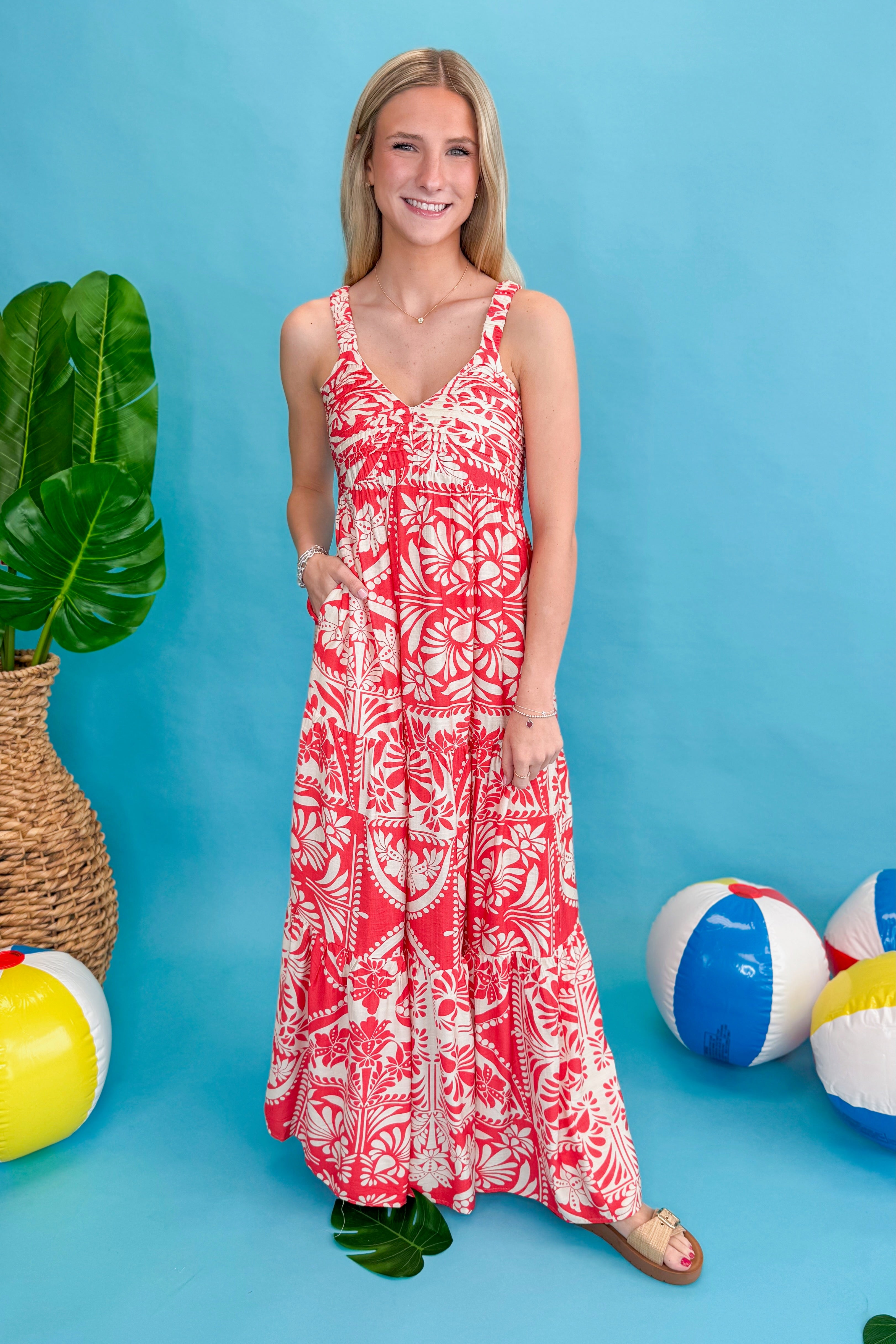 Front view of woman wearing Red Printed Sleeveless V-neck Maxi Dress against blue beachy background.