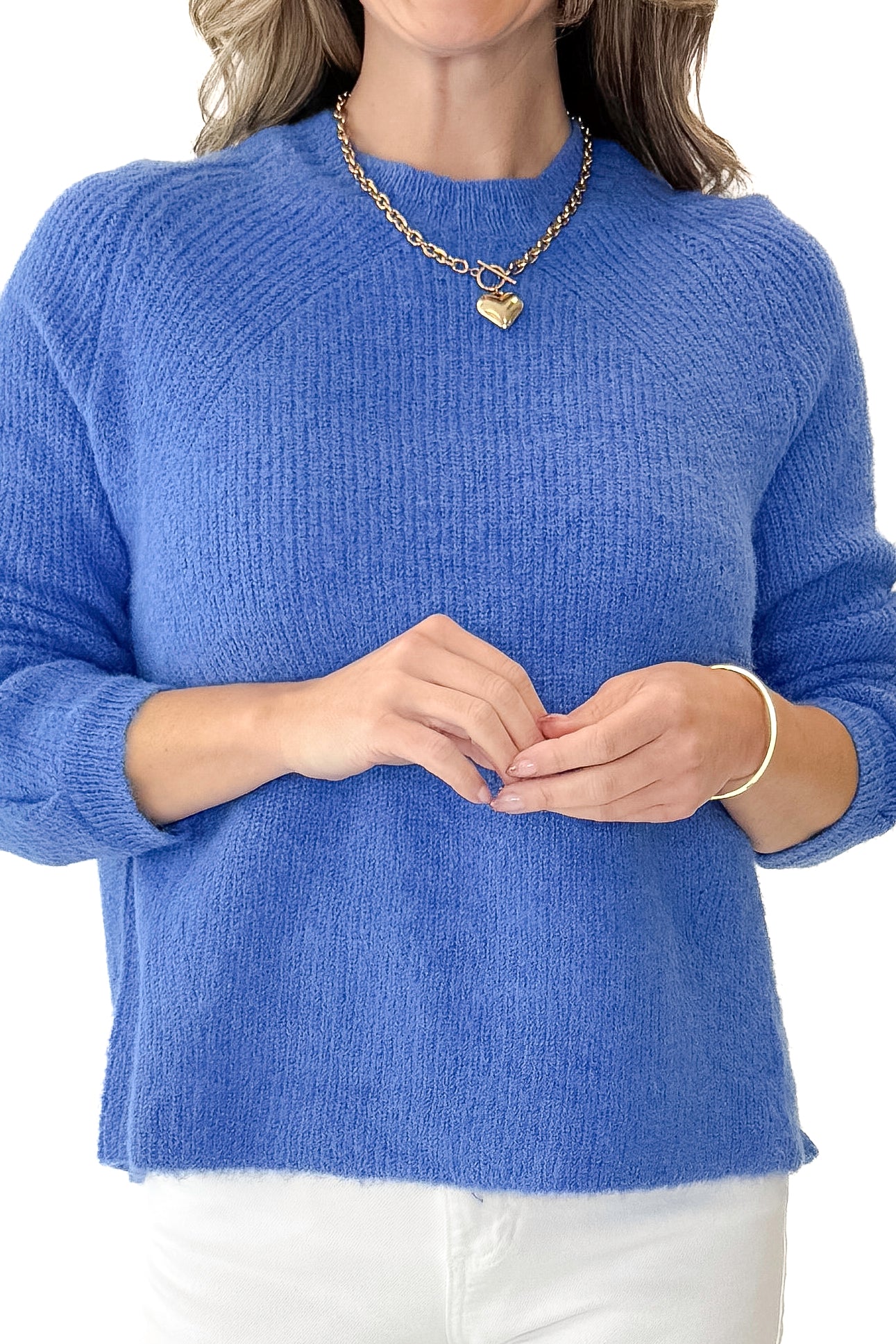 Front detail view of woman wearing Blue Ribbed Sweater with jeans against white studio background.
