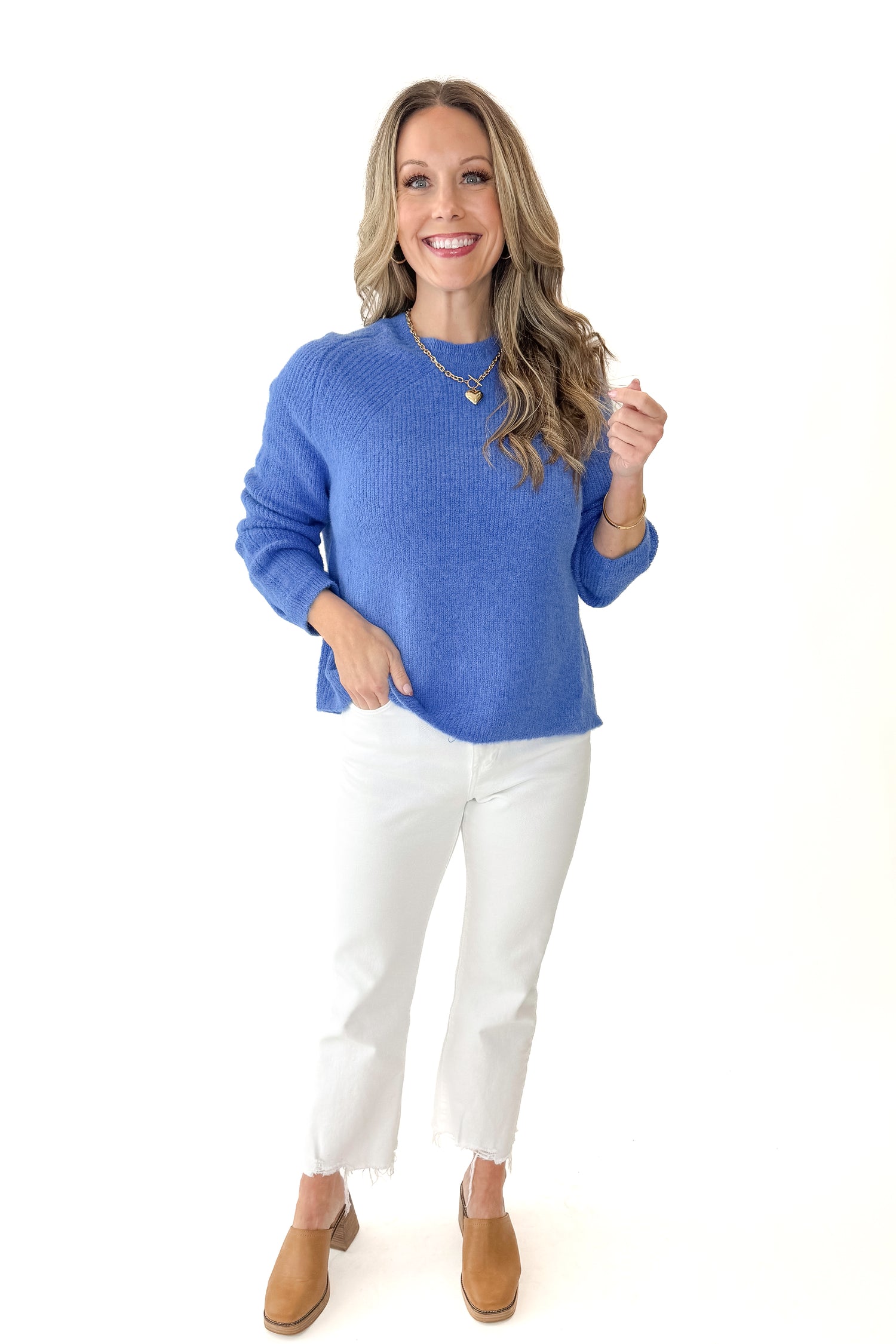 Front view of woman wearing Blue Ribbed Sweater with jeans against white studio background.