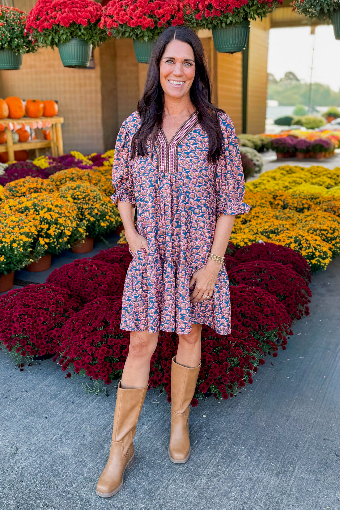 Outdoor picture of woman wearing Teal Printed Puff Sleeve Dress by She + Sky with mums in the background.