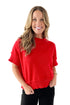 Front view of woman wearing red half sleeve sweater with jeans against white studio background.