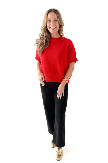 Front view of woman wearing red half sleeve sweater with jeans against white studio background.