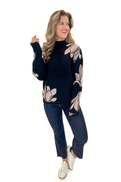 Front view of woman wearing Black With Mauve Floral Print Sweater with jeans against white studio background.