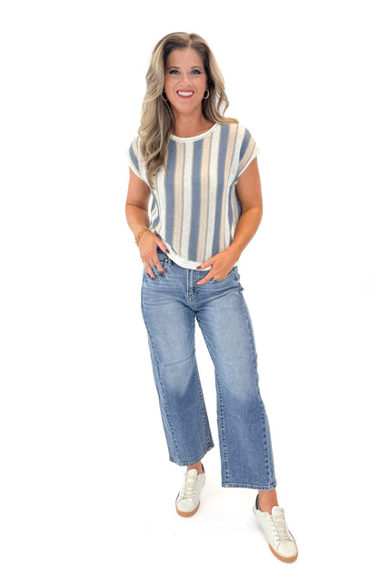 Front view of woman wearing Blue &amp; Tan Striped Short Sleeve Sweater with jeans against white studio background.