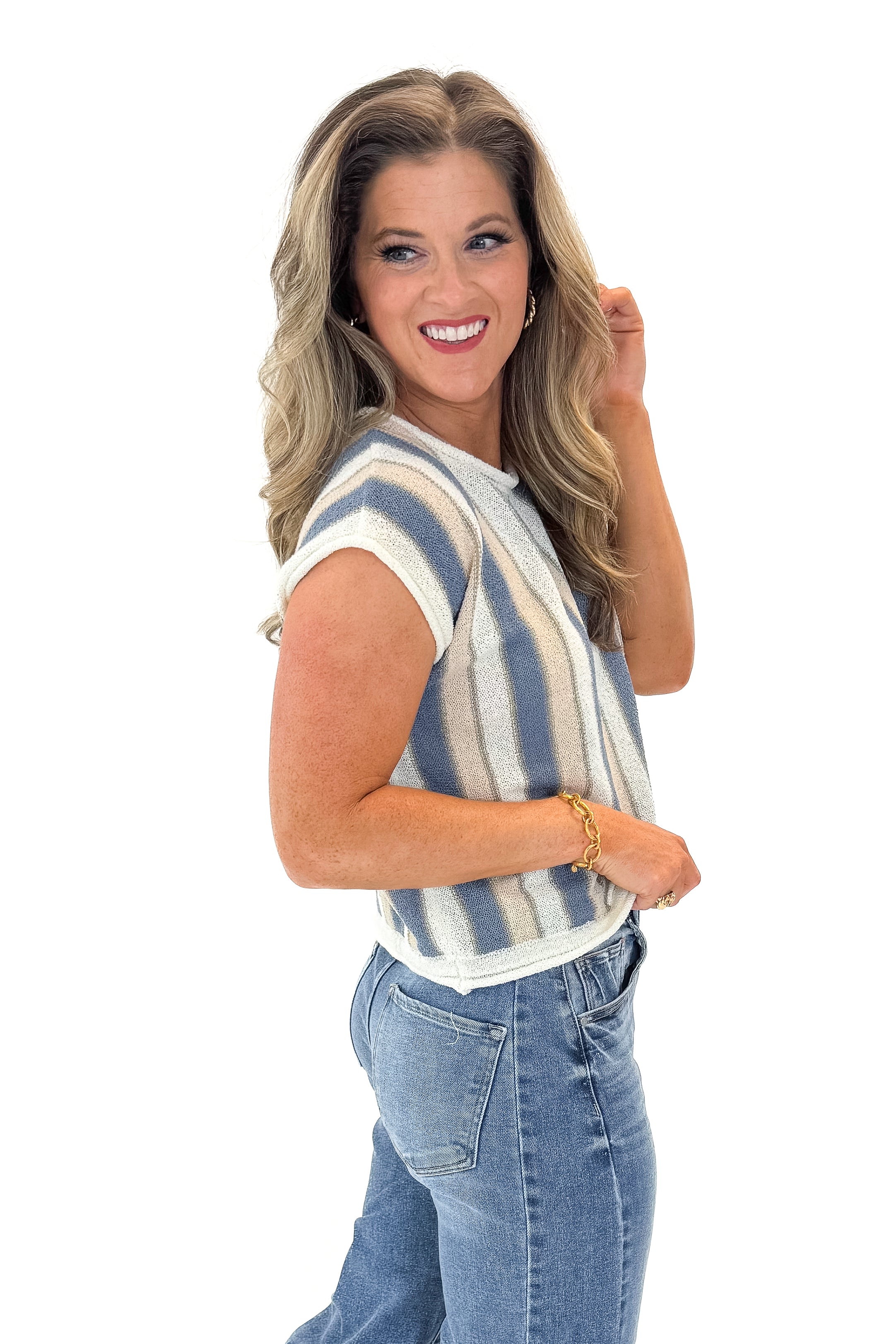 Side view of woman wearing Blue &amp; Tan Striped Short Sleeve Sweater with jeans against white studio background.