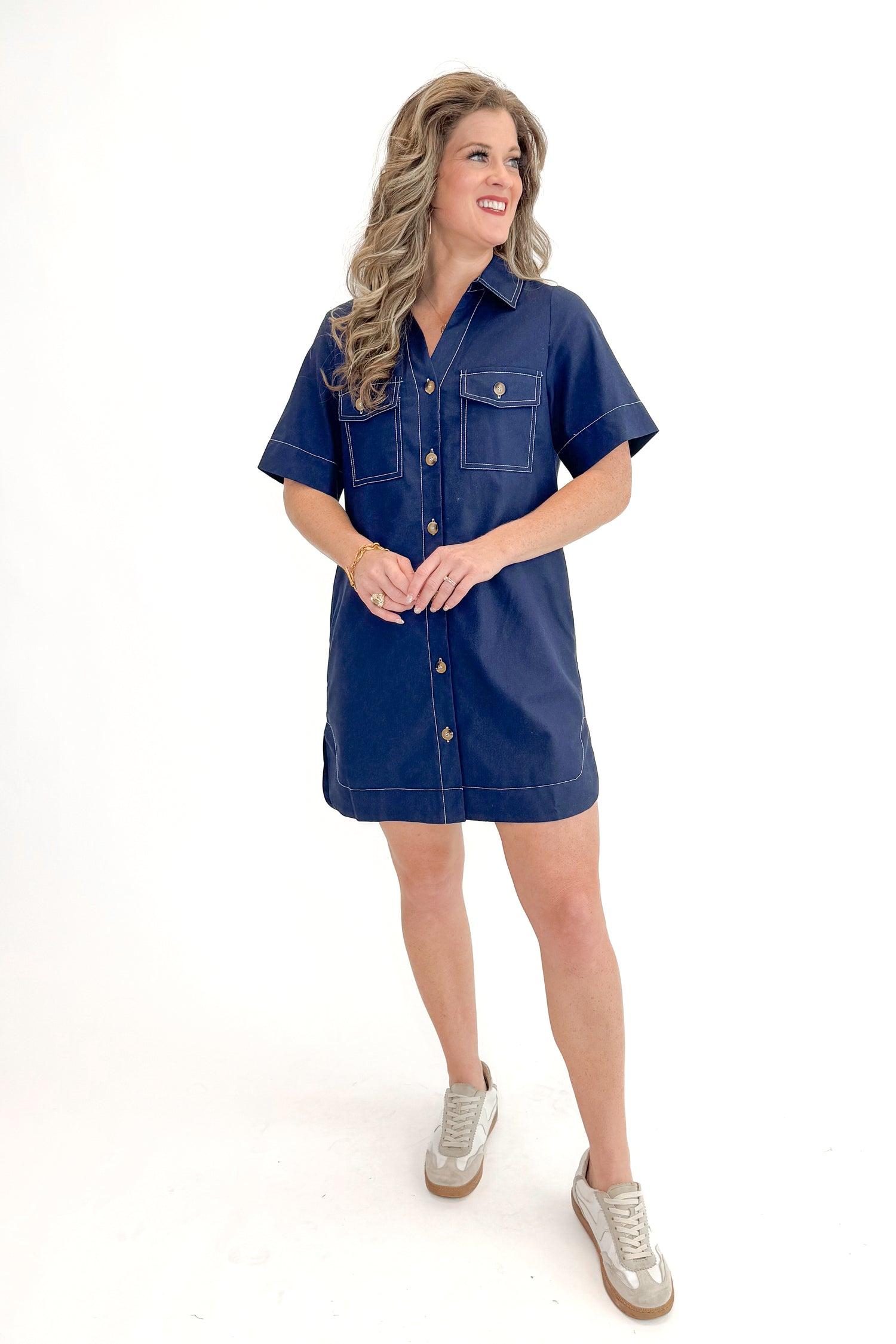 Front view of woman wearing Navy Stitch Detail Button Down Dress with sneakers against white studio background.