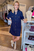 Front view of woman wearing Navy Stitch Detail Button Down Dress with boots at. a boutique.