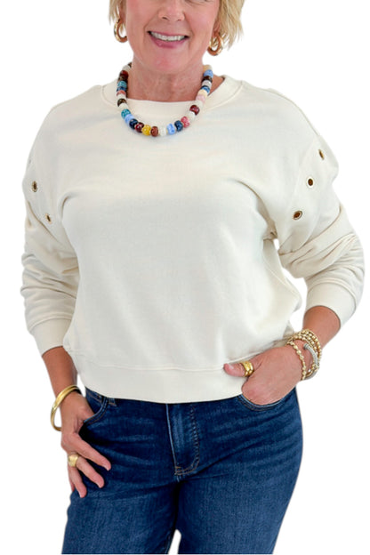 Front detail view of woman wearing Swagger Boutique’s Sandstone Axel Grommet Sweatshirt by Z Supply with jeans against white studio background.
