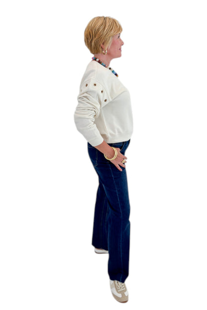 Side view of woman wearing Swagger Boutique’s Sandstone Axel Grommet Sweatshirt by Z Supply with jeans against white studio background.