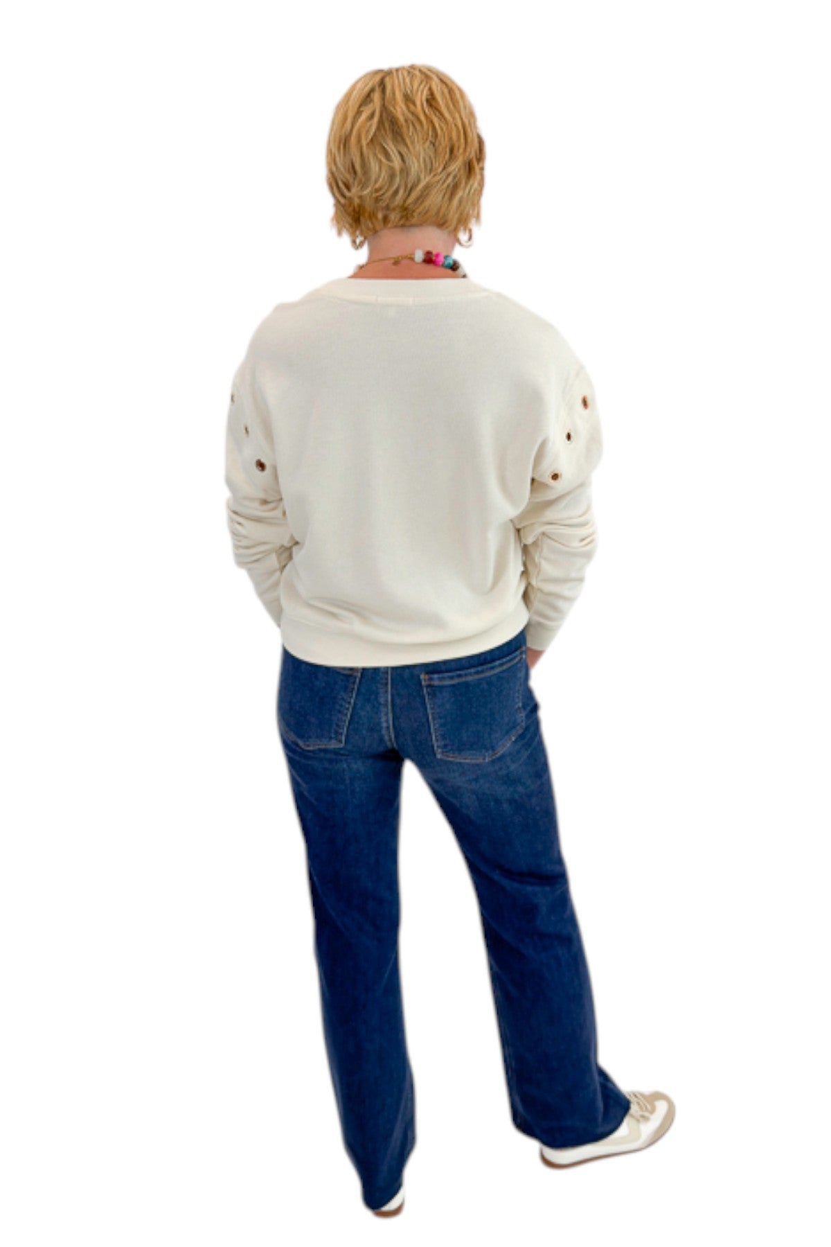 Back view of woman wearing Swagger Boutique’s Sandstone Axel Grommet Sweatshirt by Z Supply with jeans against white studio background.