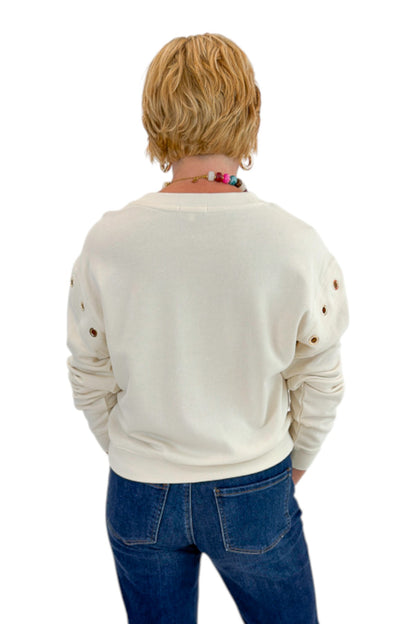 Back view of woman wearing Swagger Boutique’s Sandstone Axel Grommet Sweatshirt by Z Supply with jeans against white studio background.