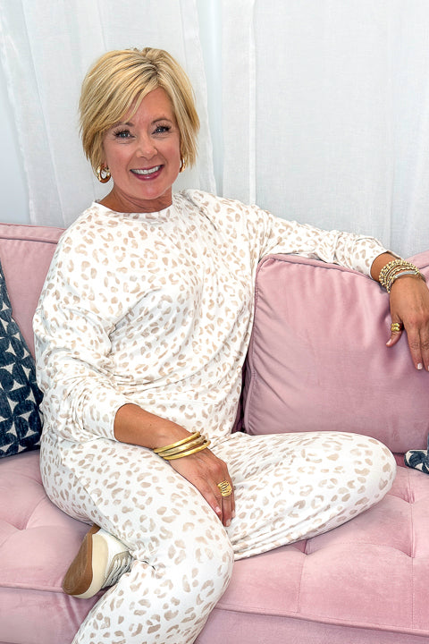 Front view of woman wearing Swagger Boutique’s Sandstone Soft Leo Long Sleeve Top with matching Joggers by Z Supply sitting on a couch.