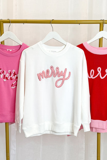 Holiday white Merry Sweatshirt hanging on a rack against a white background.