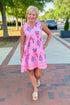 Front view of woman wearing Pink Printed Sarajane Sleeveless Dress by MudPie walking outside.