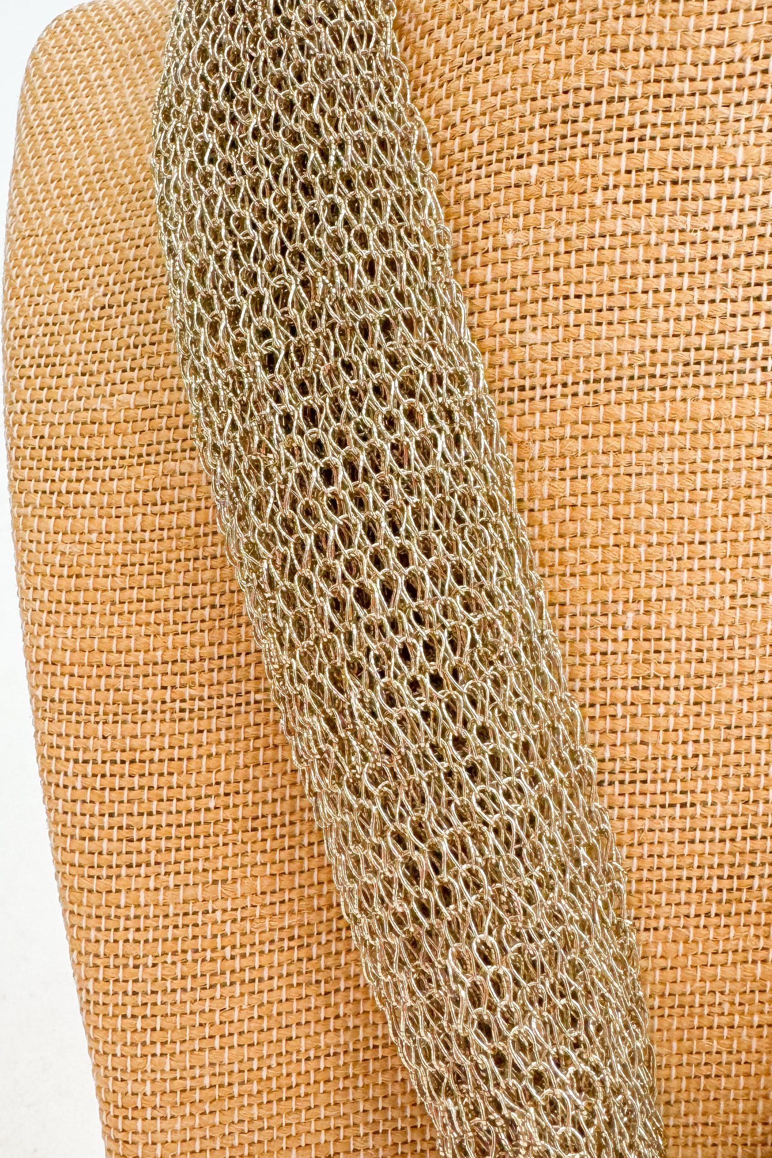 Close-up of a textured chain on a woven beige background