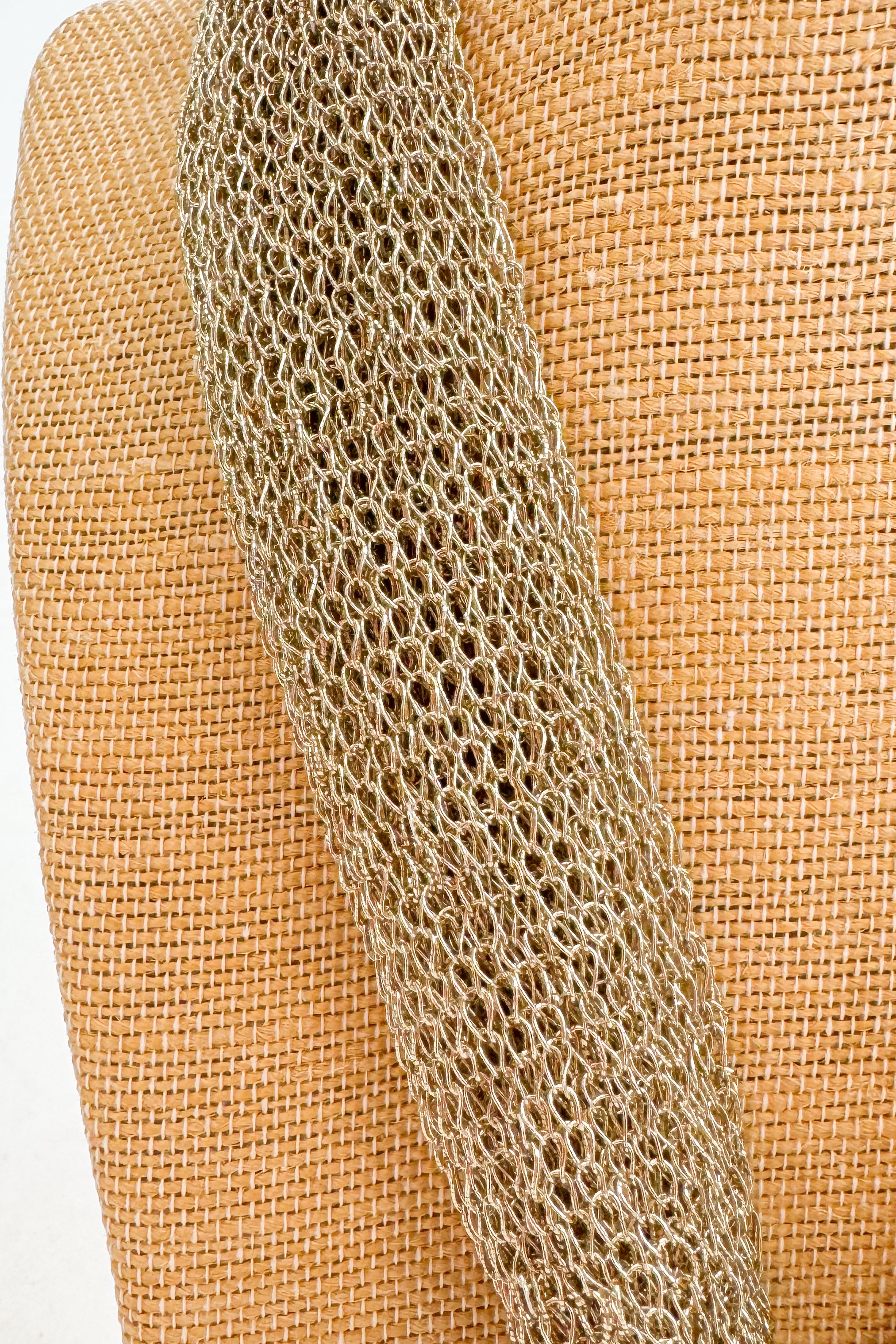 Close-up of a textured chain on a woven beige background