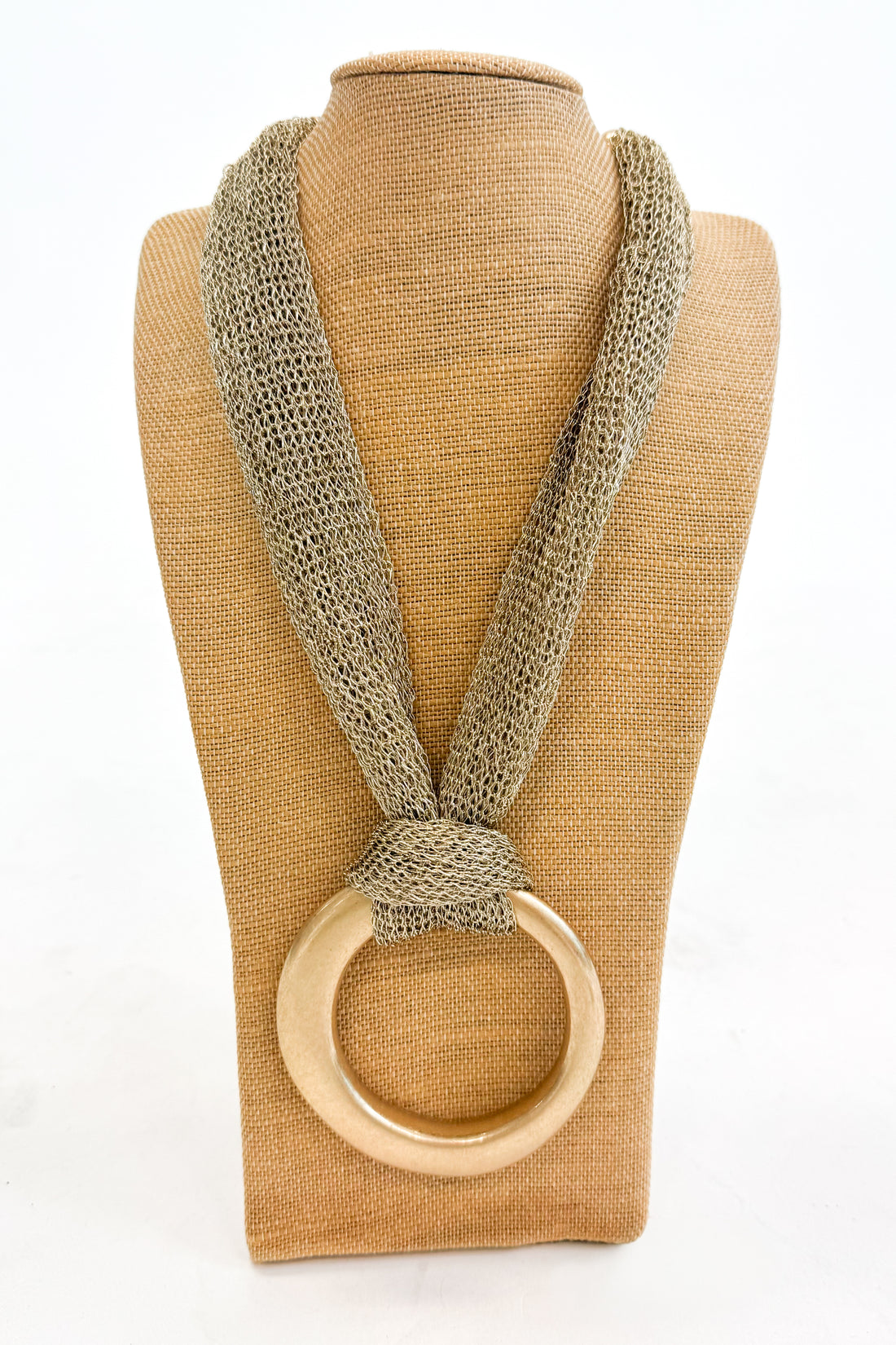 Textured mesh chain with a gold ring on a beige mannequin against a white background