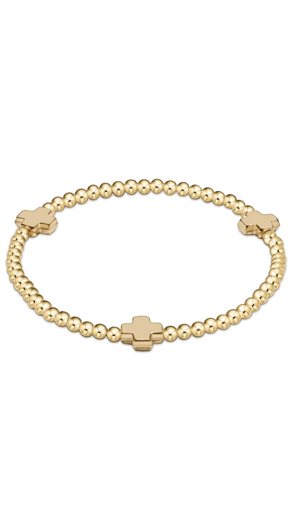 A gold beaded bracelet with three flat, polished cross-shaped charms spaced along the band, displayed on a clean white background.