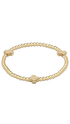 A gold beaded bracelet with three flat, polished cross-shaped charms spaced along the band, displayed on a clean white background.