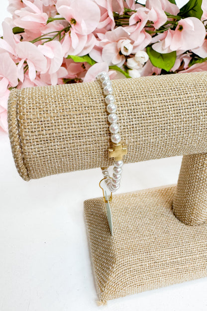 Pearl bracelet on a burlap stand with pink flowers in the background