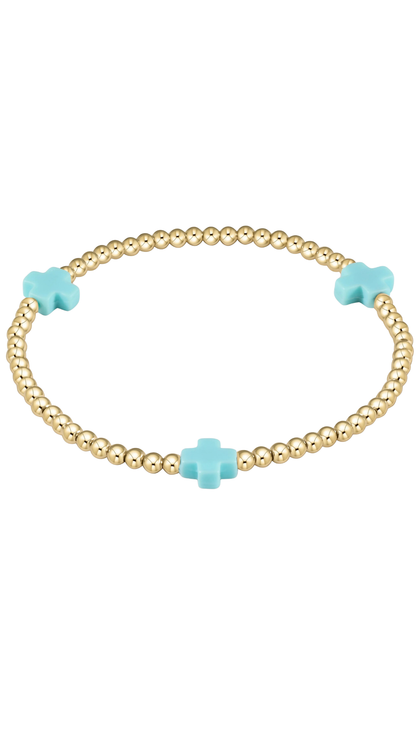 A gold beaded bracelet with three light blue cross charms, displayed on a clean white background.