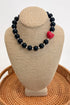 Black beaded necklace with a red heart pendant on a beige bust