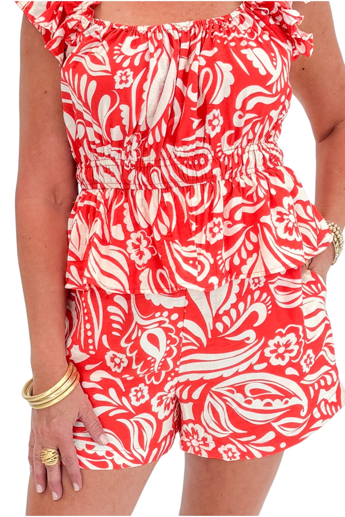 Front detail view of woman wearing Swagger Boutique’s Coral Printed Smocked Peplum Tank with matching Coral Printed Shorts against white studio background.