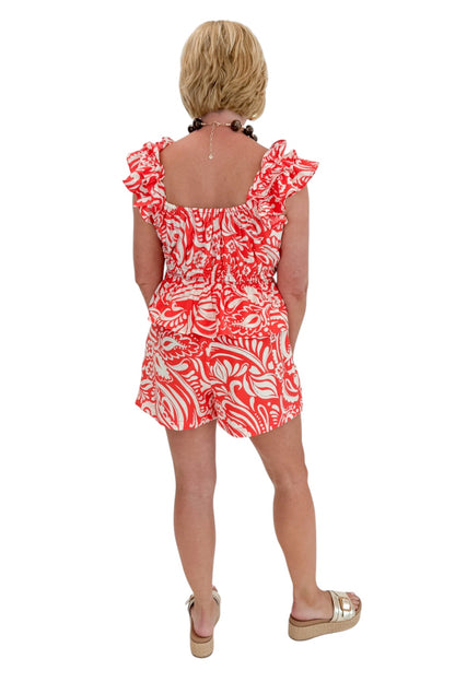 Back view of woman wearing Swagger Boutique’s Coral Printed Smocked Peplum Tank with matching Coral Printed Shorts against white studio background.