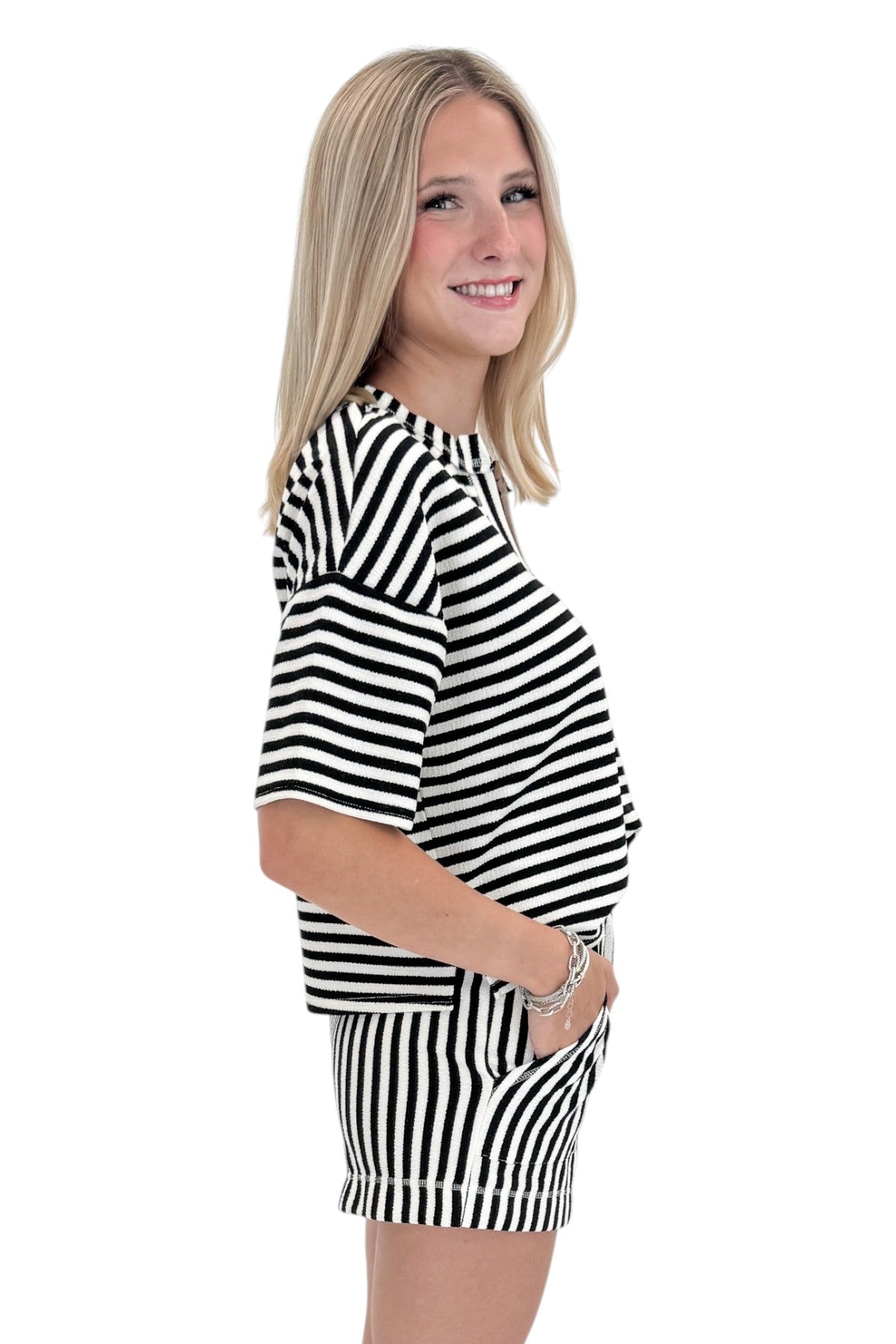 Side view of woman wearing Swagger Boutique’s Black &amp; White Striped Lounge Shorts with matching shorts against white studio background.