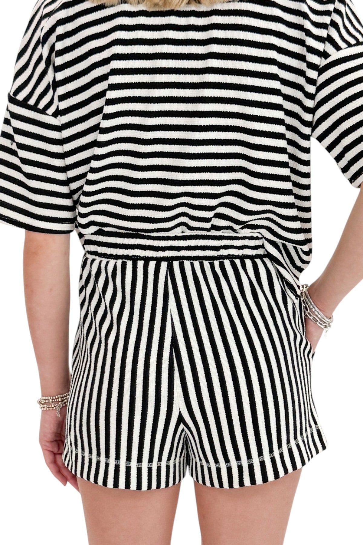 Back detail view of woman wearing Swagger Boutique’s Black &amp; White Striped Lounge Shorts with matching shorts against white studio background.