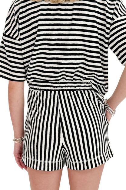 Back detail view of woman wearing Swagger Boutique’s Black &amp; White Striped Lounge Shorts with matching shorts against white studio background.
