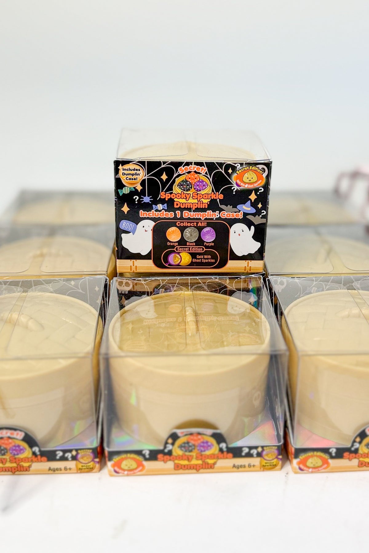 Three unopened packages of dumpling squishies in a grid, with one package standing upright in the center to show the front label.