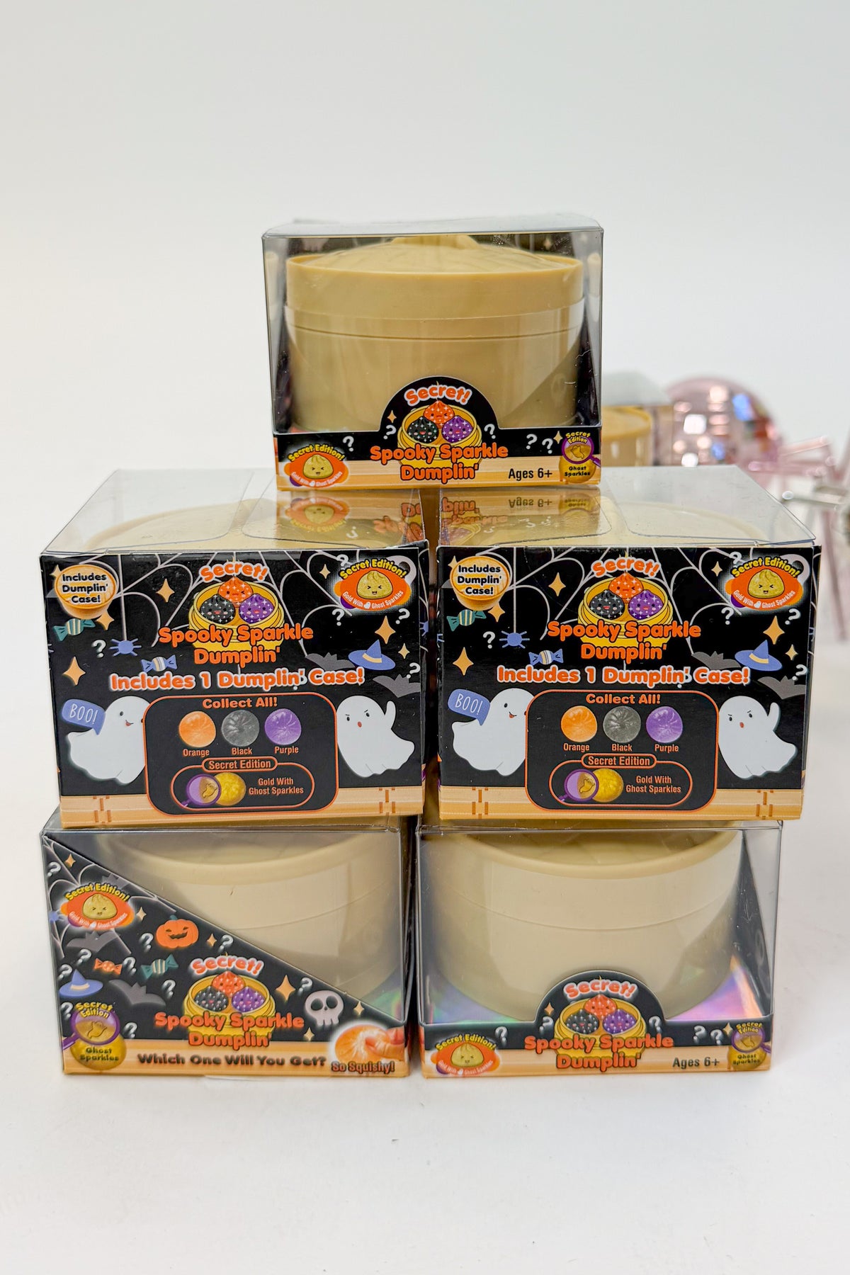 Four Halloween-themed dumpling mystery boxes stacked in a 2x2 grid, with one additional box on top. The packaging features spooky graphics like ghosts, pumpkins, and spiderwebs, and the boxes are clear plastic showing the beige pots inside.