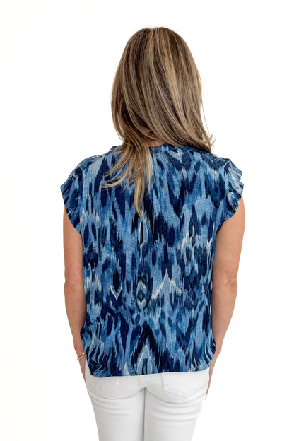 Back view of woman wearing Navy &amp; Blue Printed V-Neck Top with jeans against white studio background.