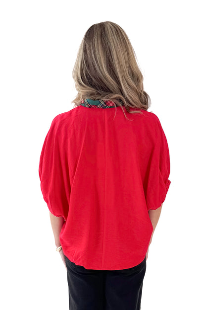Back view of woman wearing Red With Tartan Lining Dolman Sleeve Top with jeans against white studio background.
