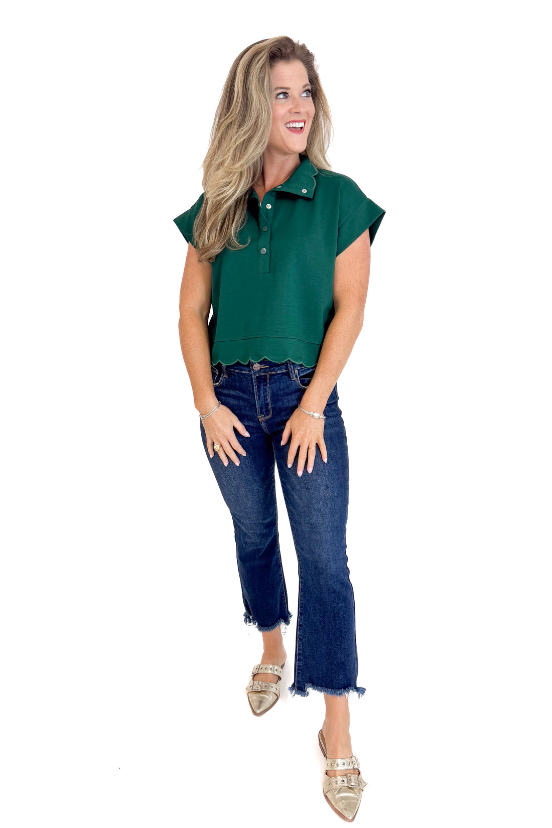 Woman wearing a green sleeveless top and blue jeans on a white background